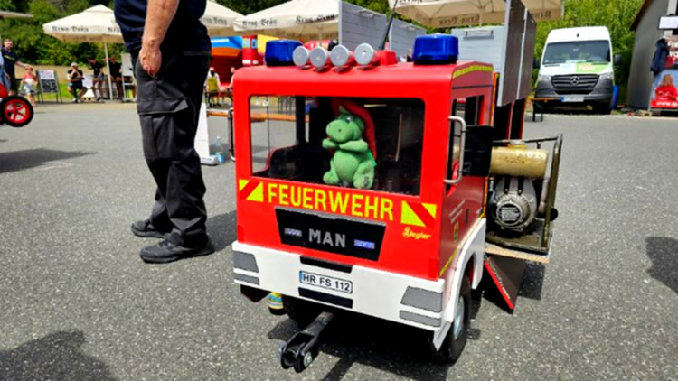 Kinder steuern kleine rote Feuerwehrautos.